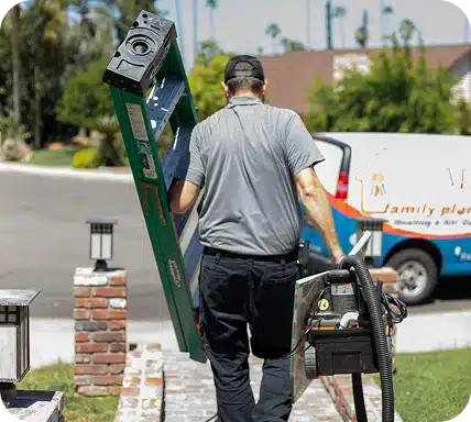 A man in a gray shirt and black cap carries a green ladder and equipment, walking away from a "Family plan" van.